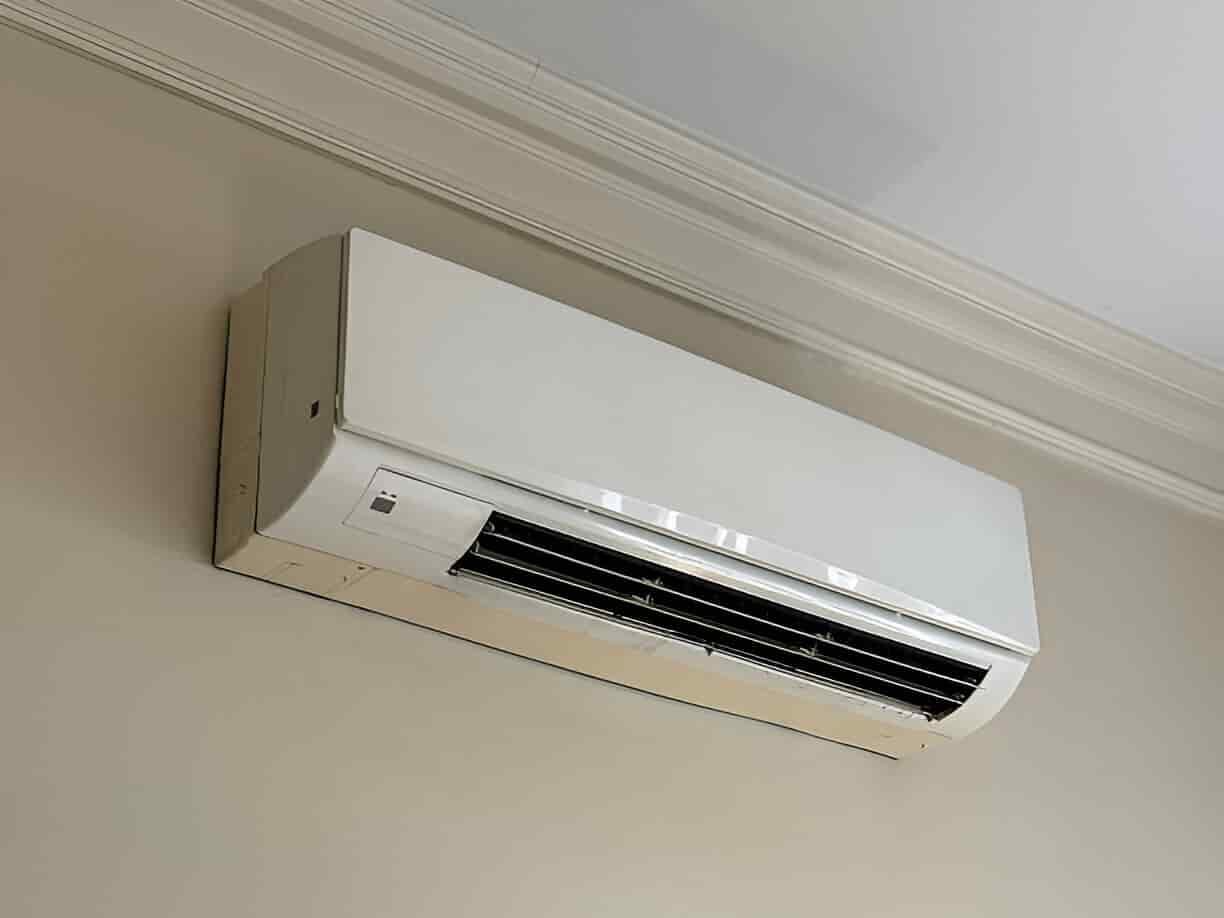 White wall-mounted air conditioning unit with black air vents