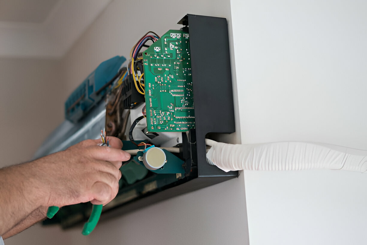 Technician repairing electronic circuit board with green pliers
