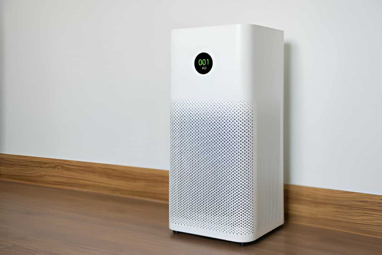 White air purifier with digital display sitting on wooden floor