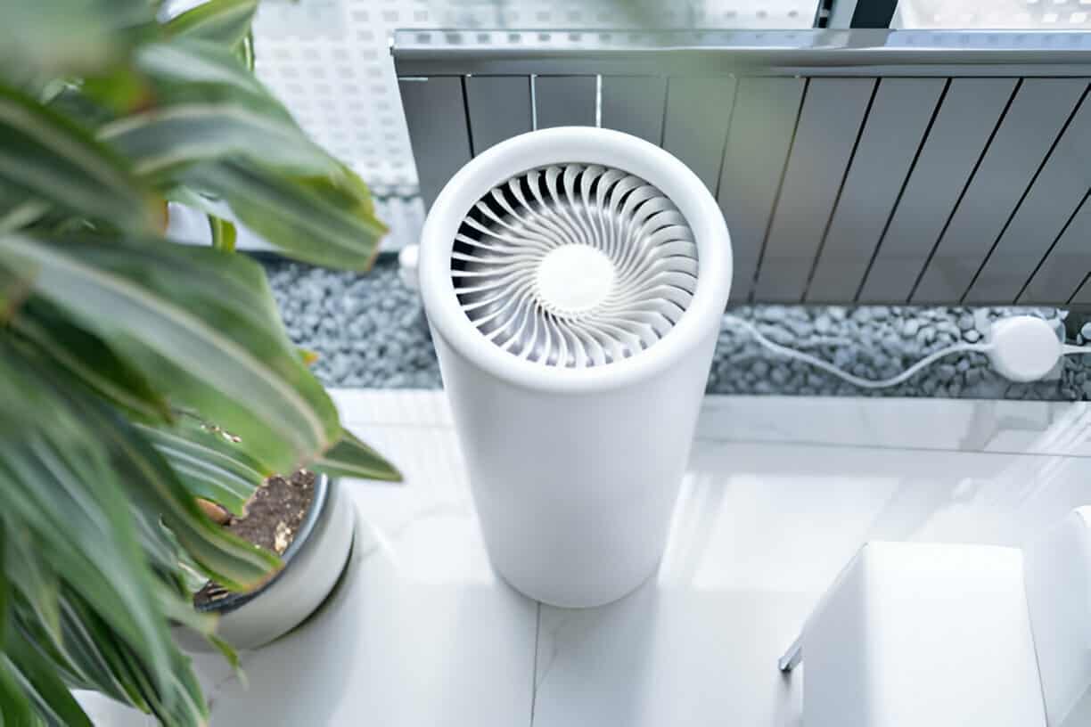 White cylindrical air purifier with spiral fan design near green plant