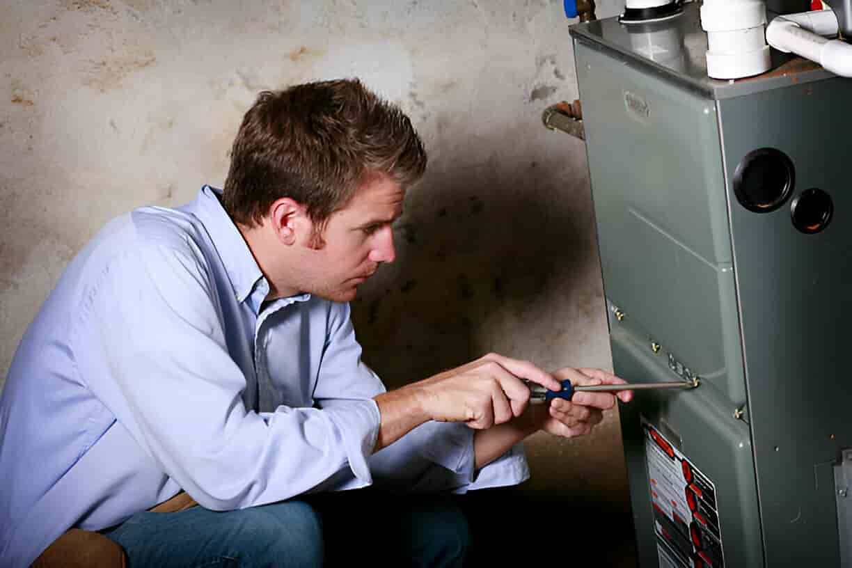Technician in denim jacket inspecting radiator with tool belt