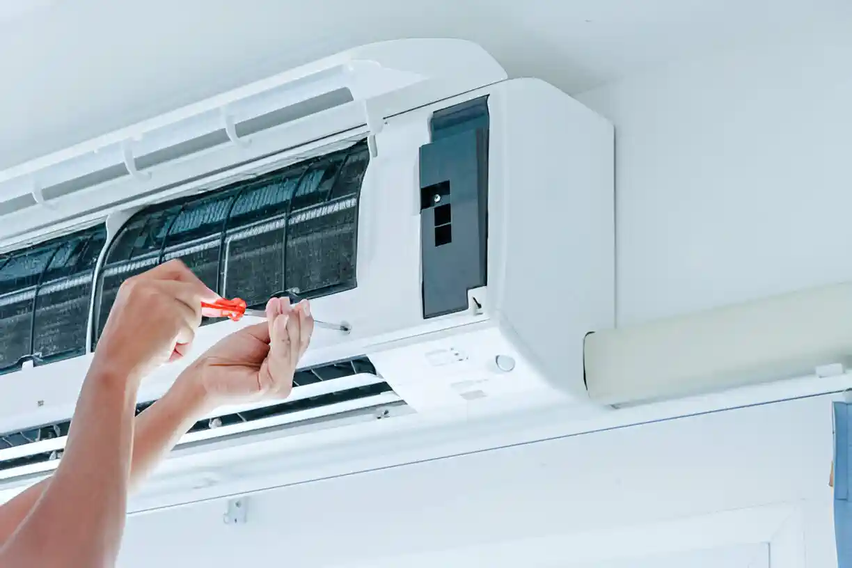 Hands repairing or maintaining a wall-mounted air conditioning unit