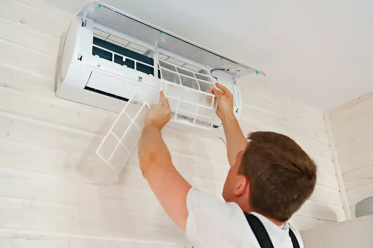 Technician cleaning and maintaining a wall-mounted air conditioning unit
