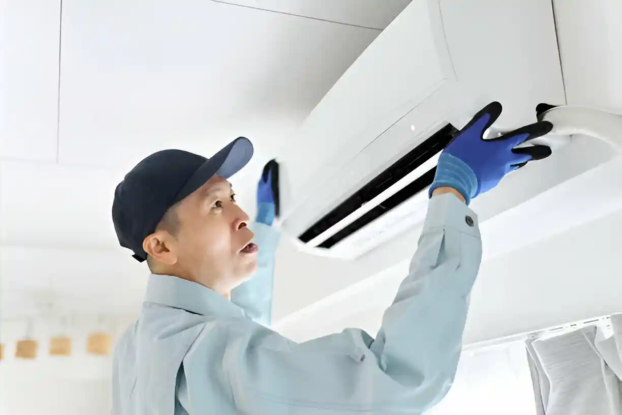 Worker in blue gloves installing or repairing ceiling air conditioning unit