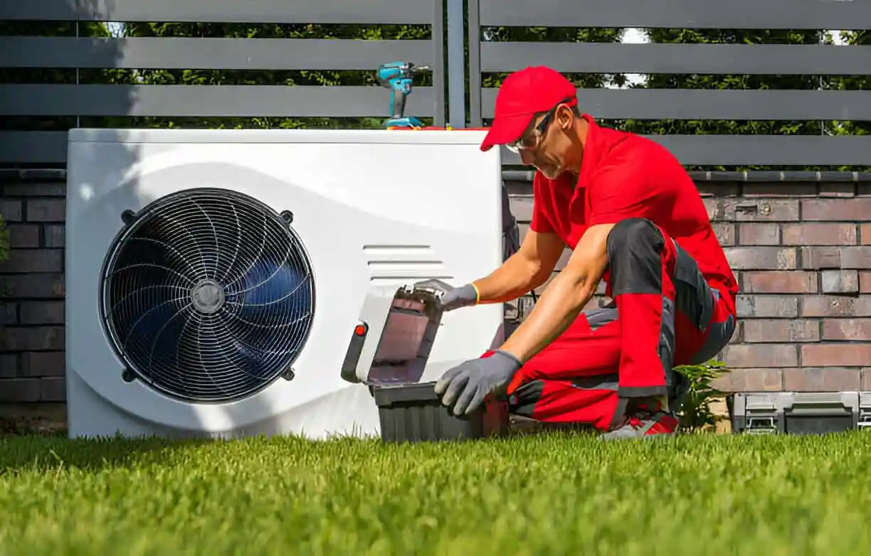 Technician in red uniform repairing an outdoor heat pump unit