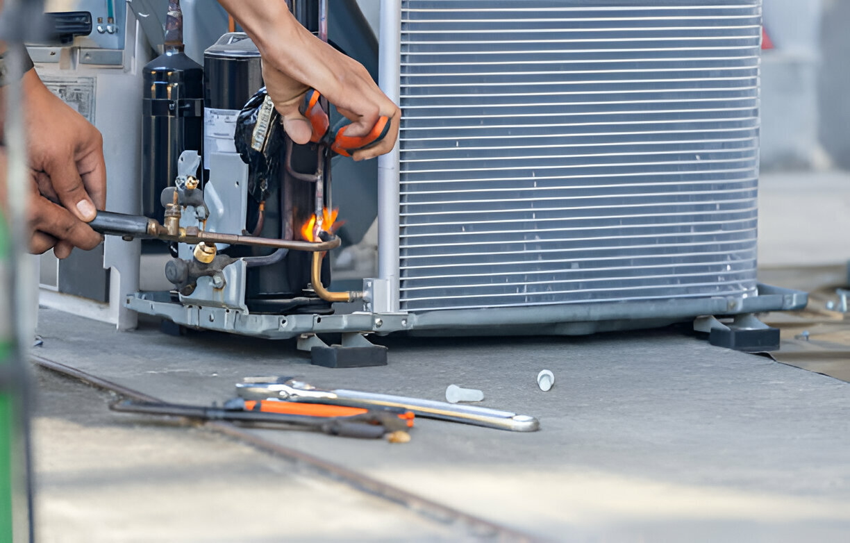 Technician repairing air conditioner with flame torch and tools