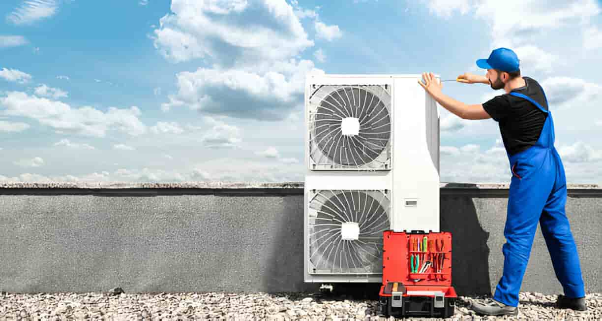 Technician installing air conditioning unit on rooftop under cloudy sky