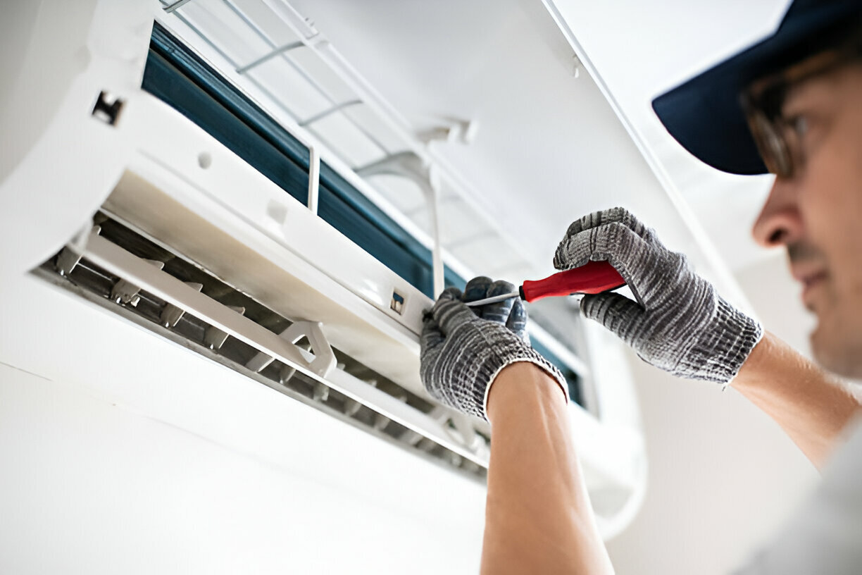 Technician repairing air conditioning unit with screwdriver