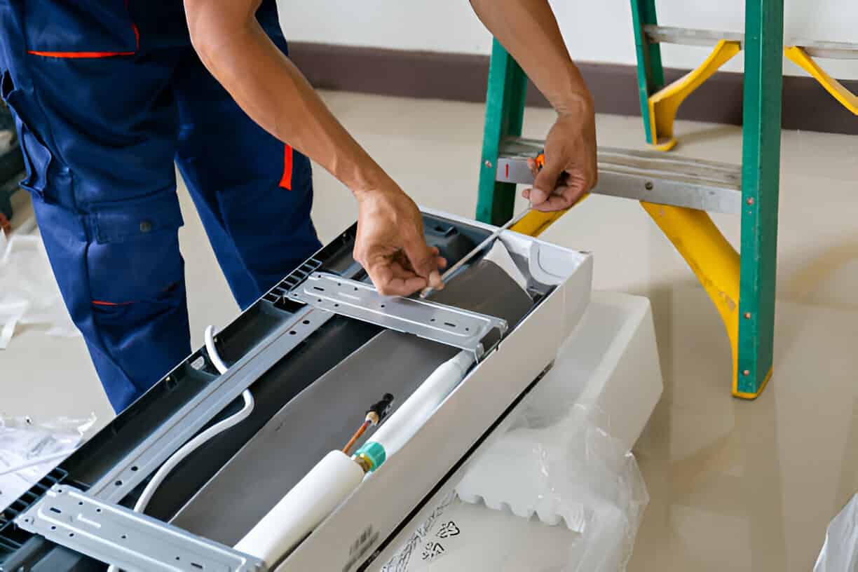 Technician installing components in electrical panel with ladder nearby