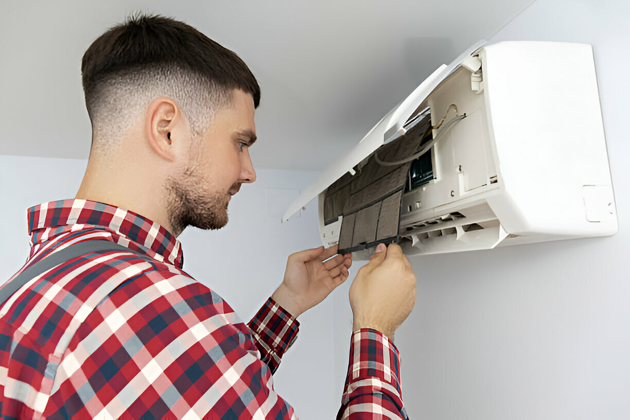 Technician in plaid shirt repairing wall-mounted air conditioning unit