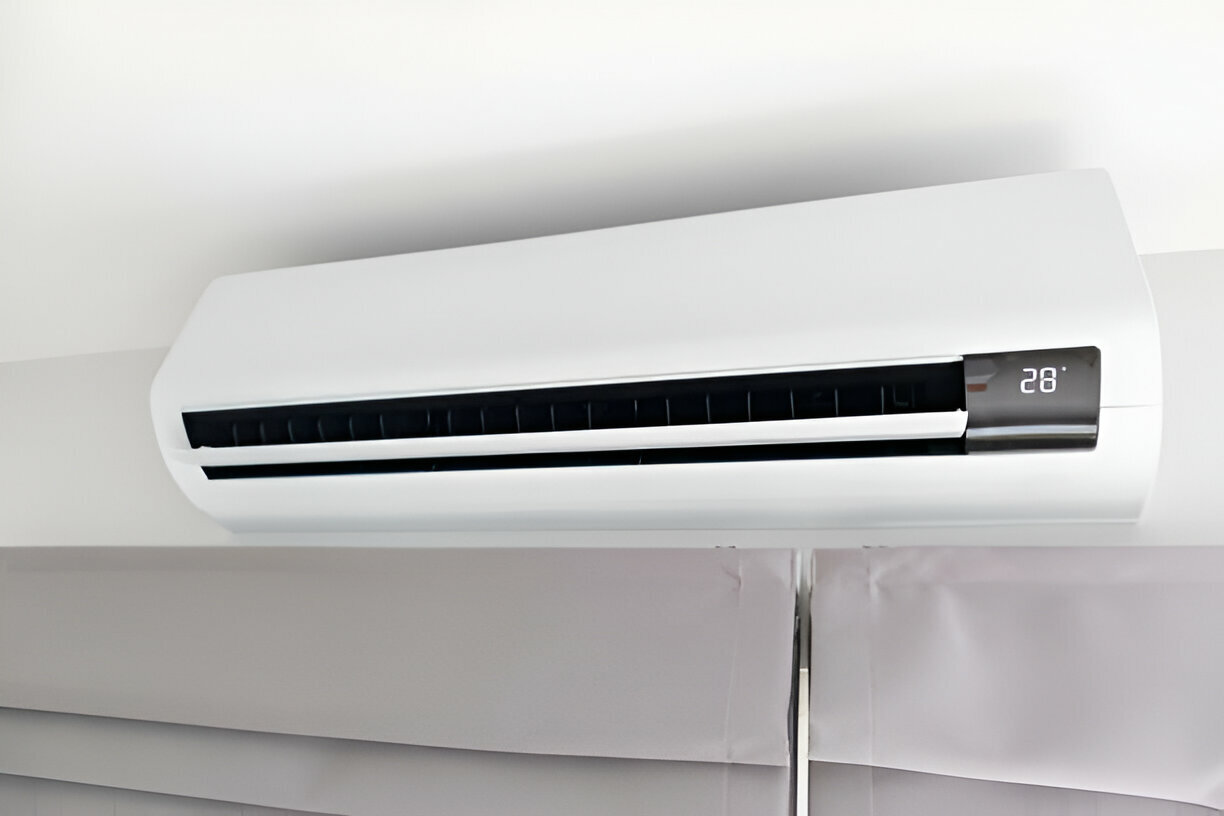 White air conditioner mounted on wall, digital display showing 28 degrees