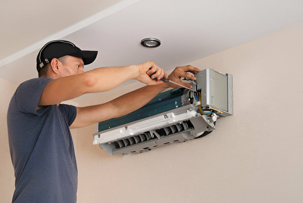 Technician installing air conditioning unit on white wall