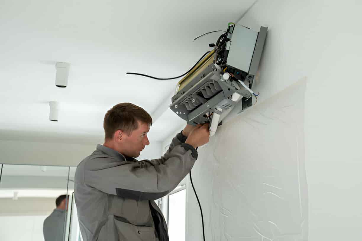 Technician installing security camera on white interior wall