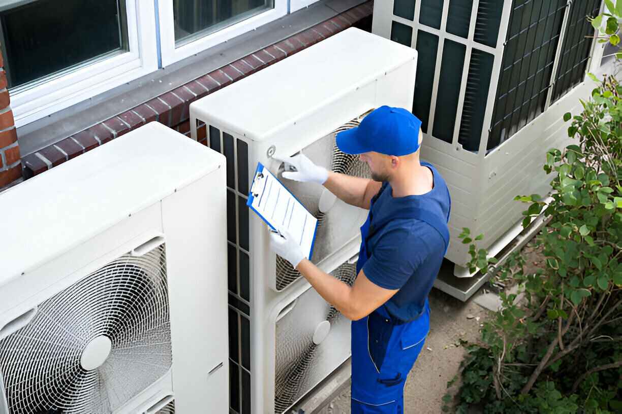 Technician in blue uniform checking outdoor air conditioning unit