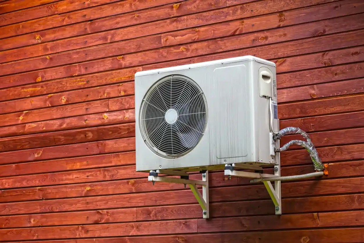 White air conditioning unit mounted on rusty red wooden wall