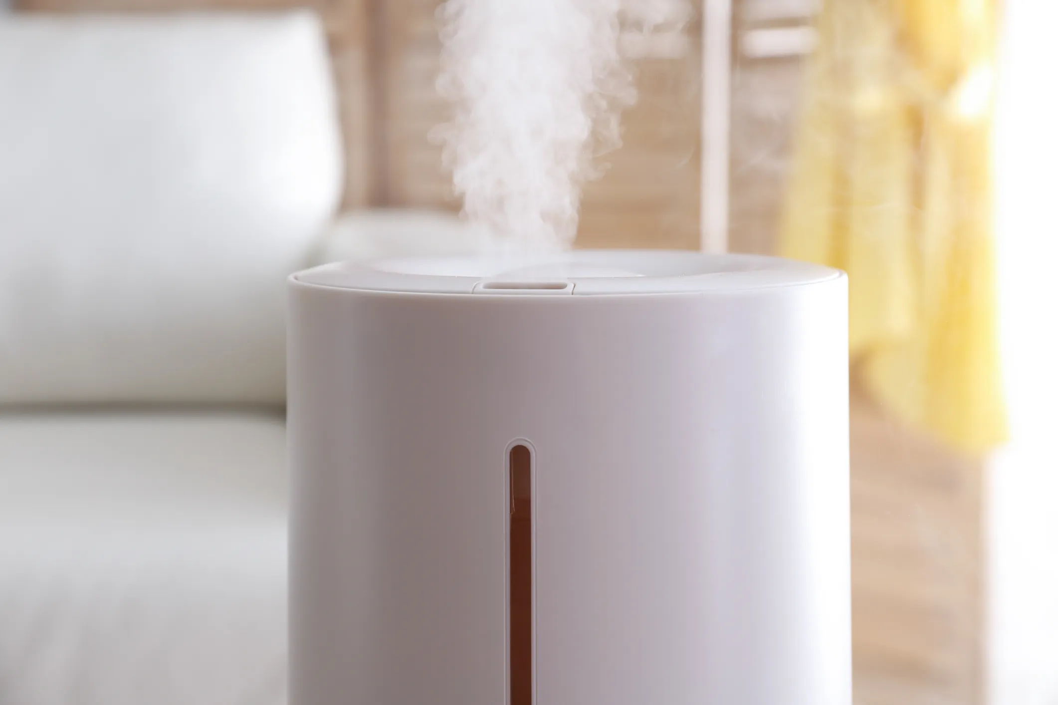 White air humidifier emitting steam in a bright, soft-lit room