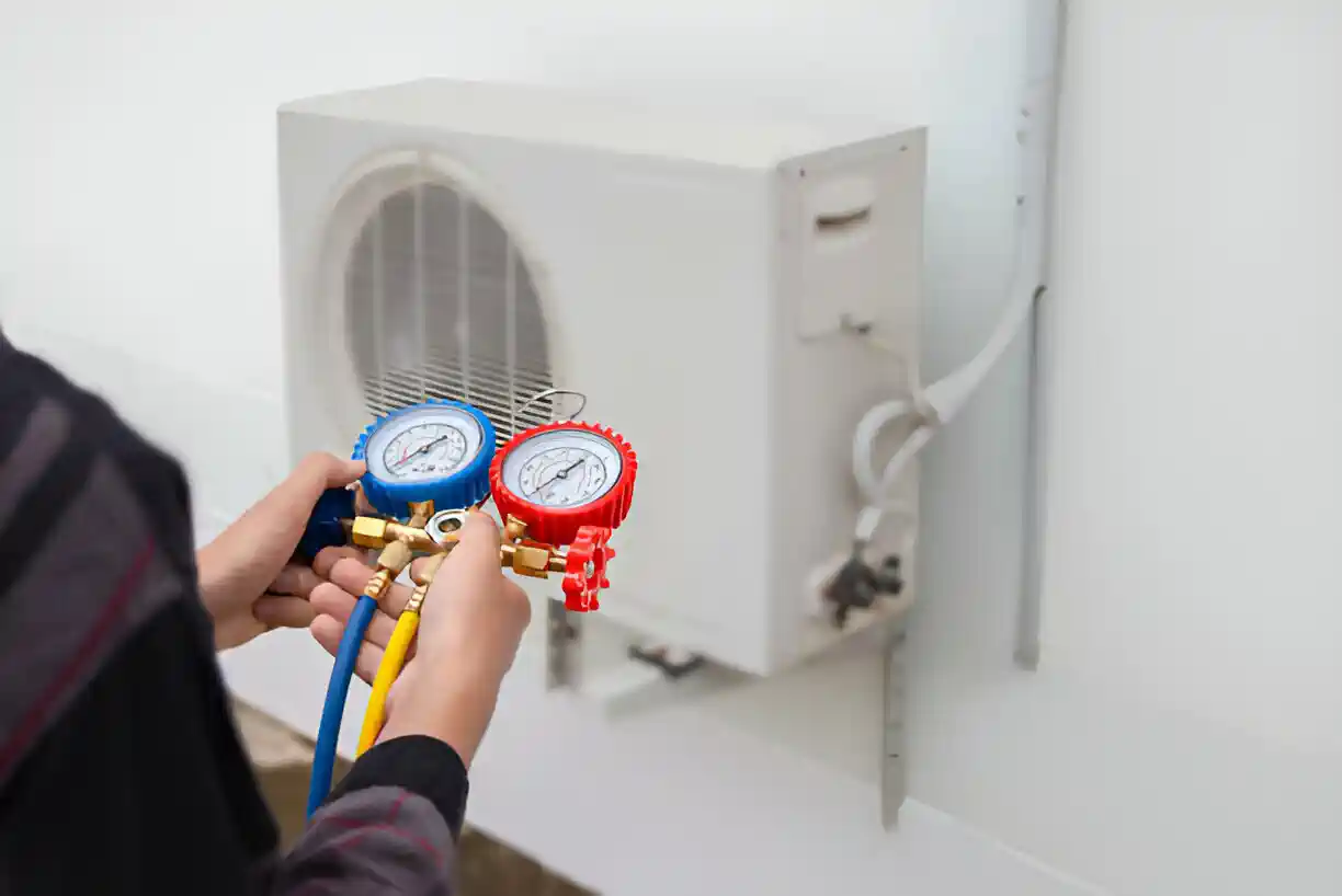 Technician checking air conditioning unit with pressure gauges