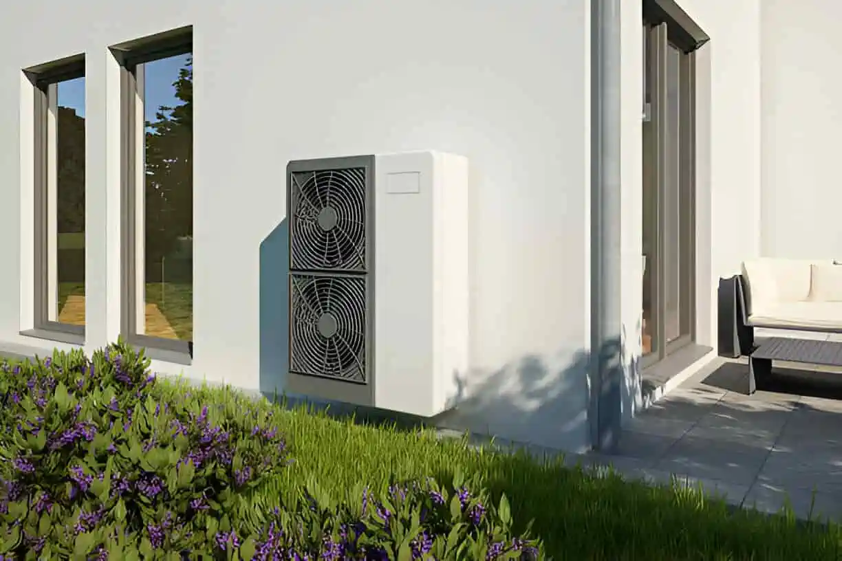 Modern heat pump outside white building with windows and flowering plants
