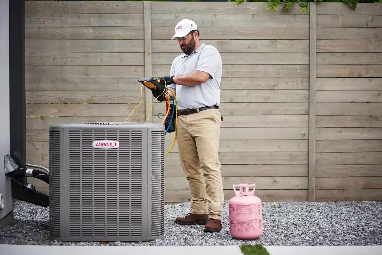 Technician servicing a Lennox air conditioning unit with refrigerant tank
