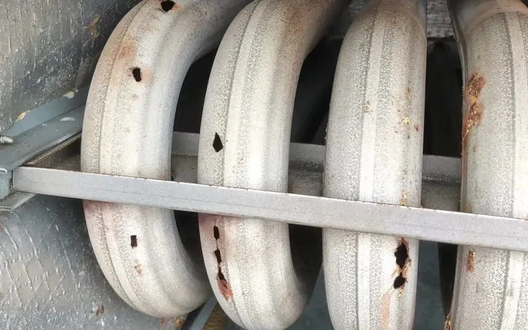 Rusty industrial pipes or tubes with holes, mounted on metal support