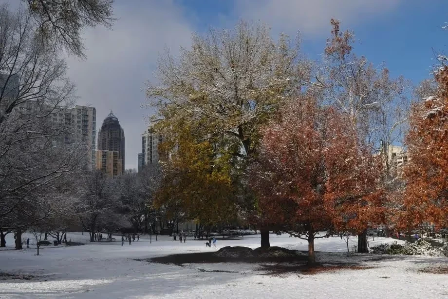 Urban park with trees transitioning from winter snow to autumn colors