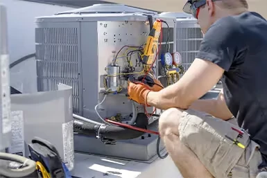 Technician repairing HVAC unit with tools and testing electrical connections
