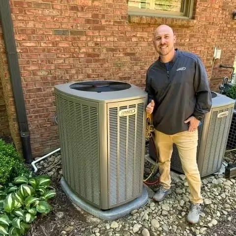 HVAC technician standing next to outdoor air conditioning units