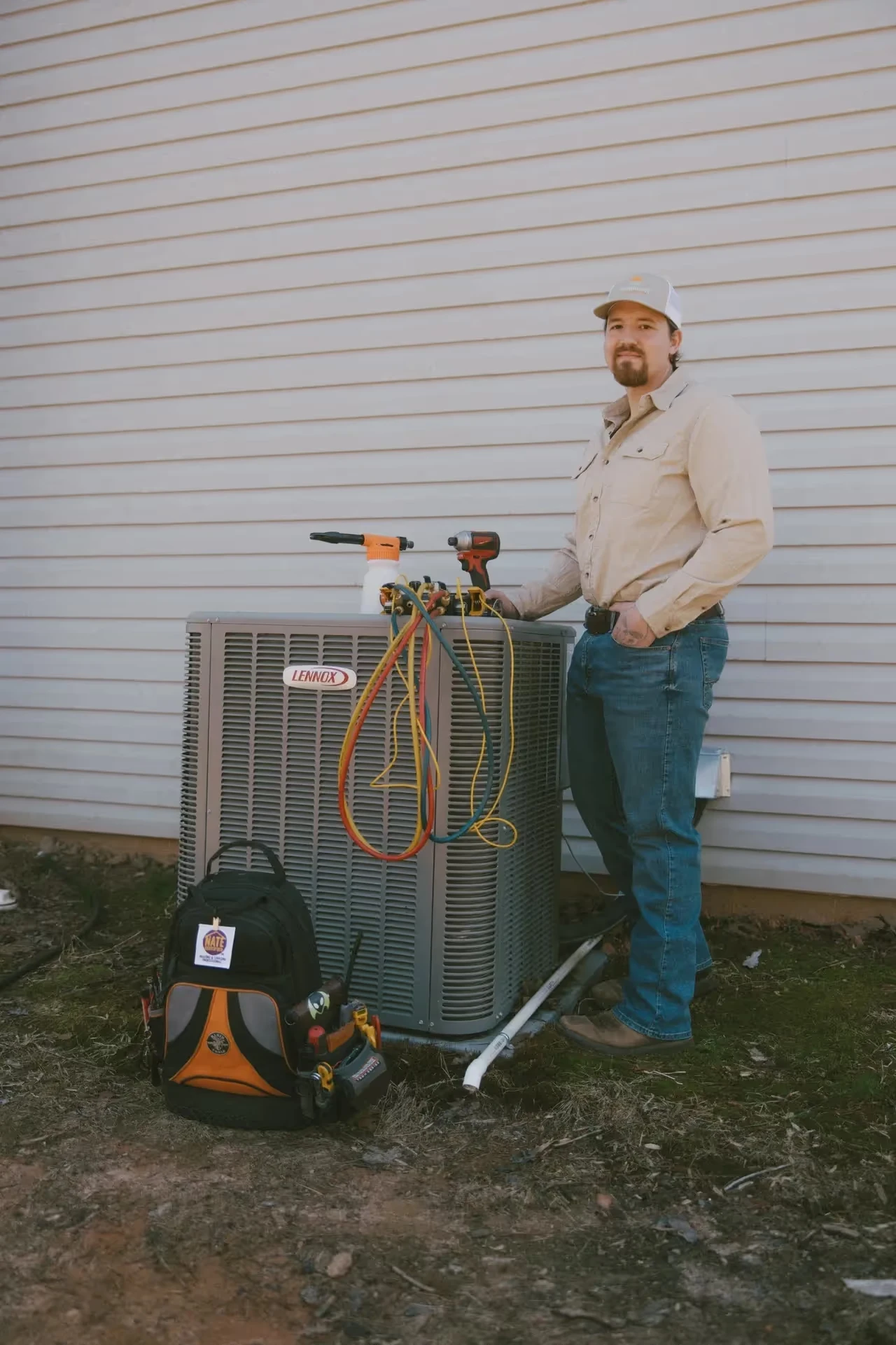 HVAC technician working on Lennox air conditioning unit with tools