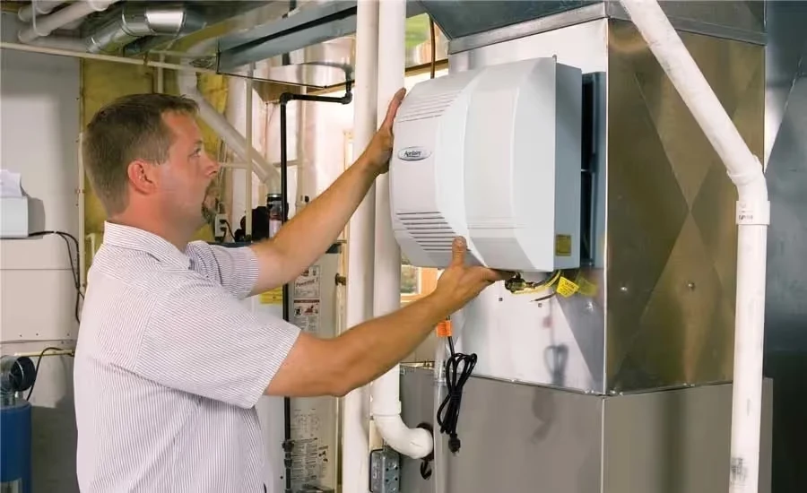 Technician installing or adjusting a white air purifier or HVAC system