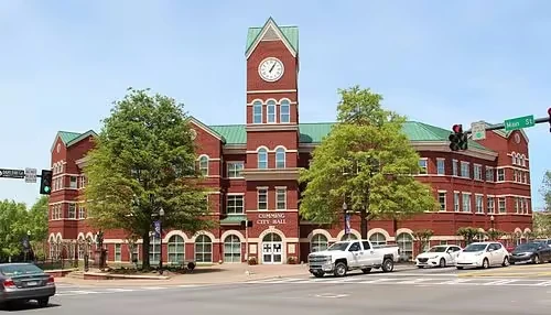 Red brick city hall with clock tower on sunny day near street intersection