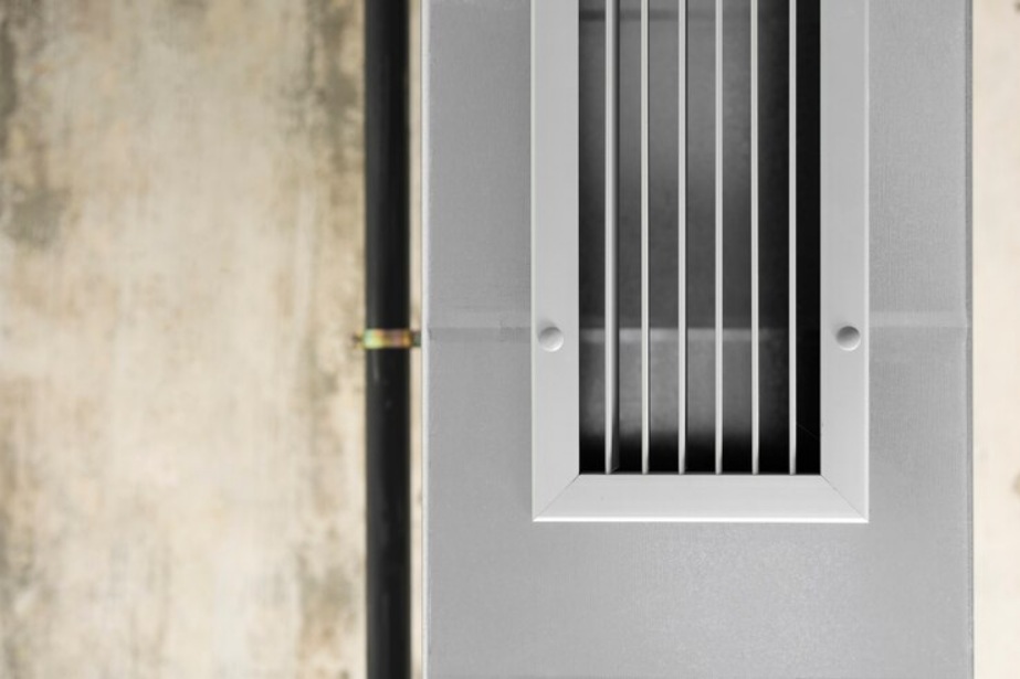 Ceiling air vent with vertical slats next to black pipe