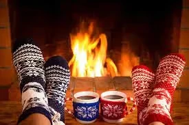 Cozy feet in patterned socks warming by a crackling fireplace with mugs