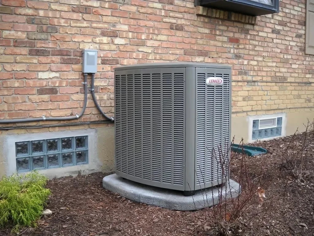 Lennox air conditioning unit installed on concrete pad next to brick house
