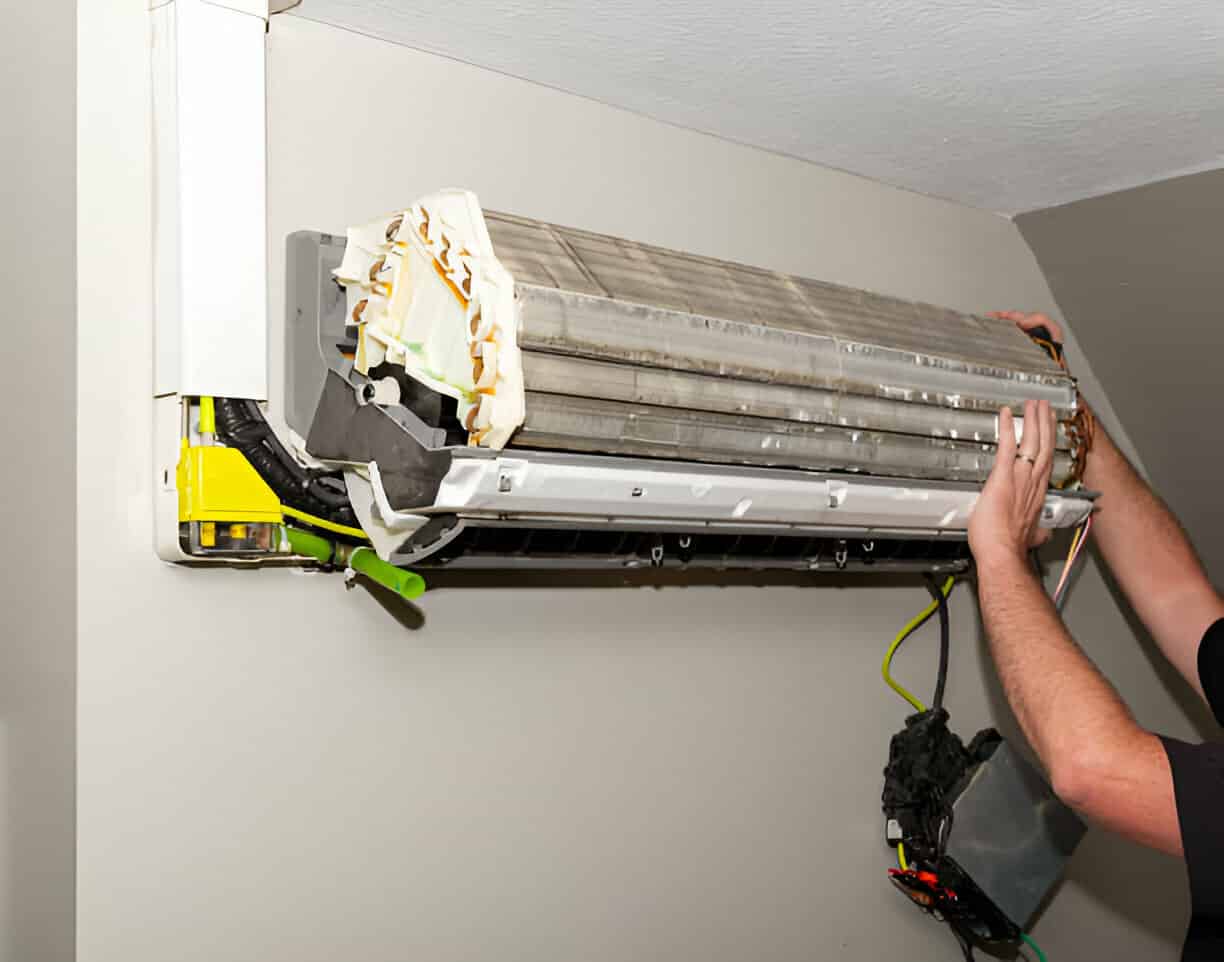 Technician repairing wall-mounted air conditioning unit with tools