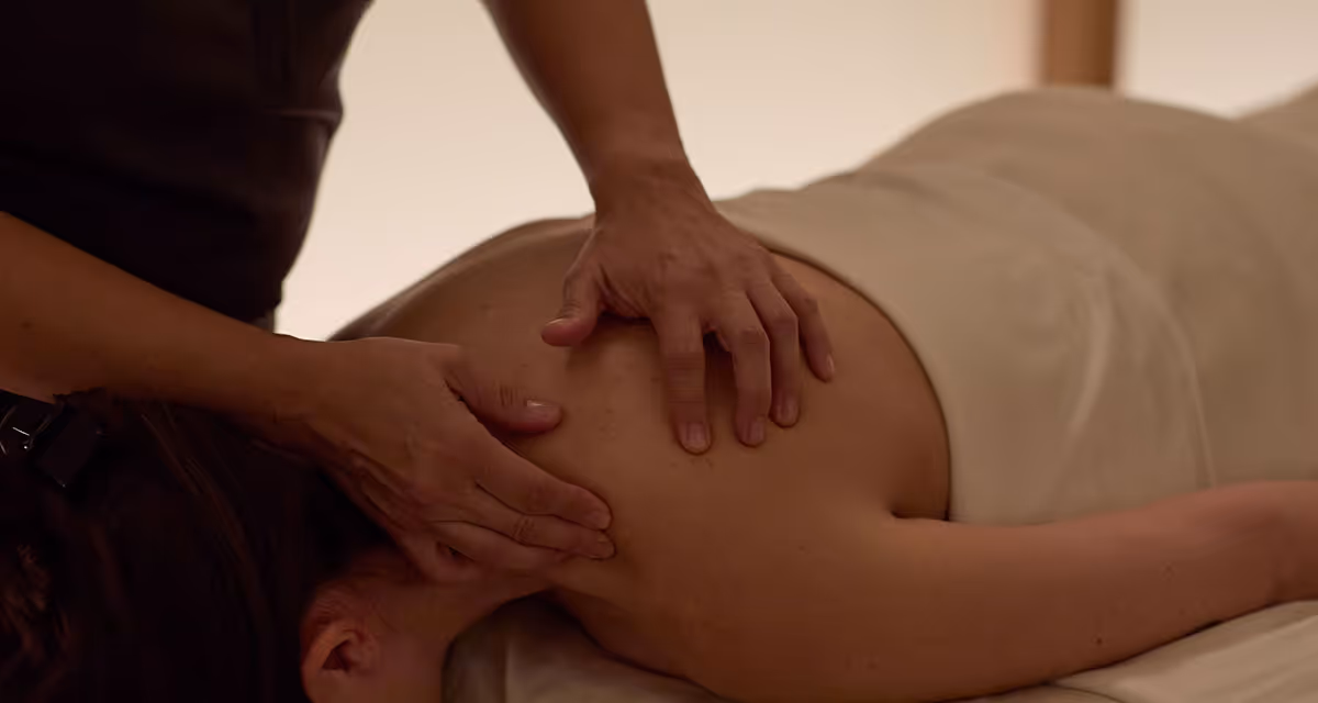 A massage therapist gives a light touch massage to guest.