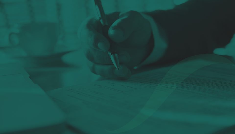 A hand working through papers as if checking compliance.