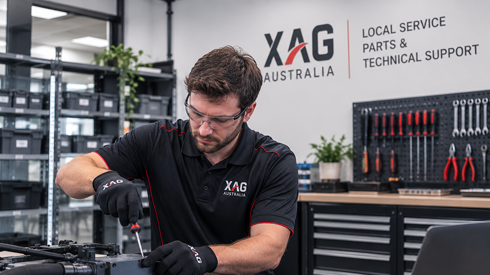 Technician wearing XAG Australia uniform working on machinery in a tool-equipped workshop.