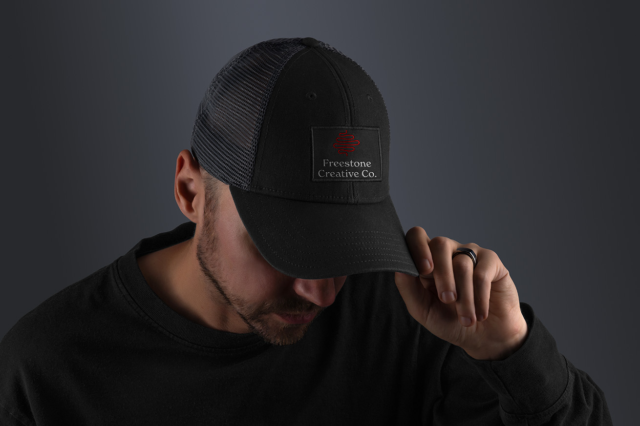 A man wearing a Freestone Creative Co. branded black trucker hat with the full logo on a patch.