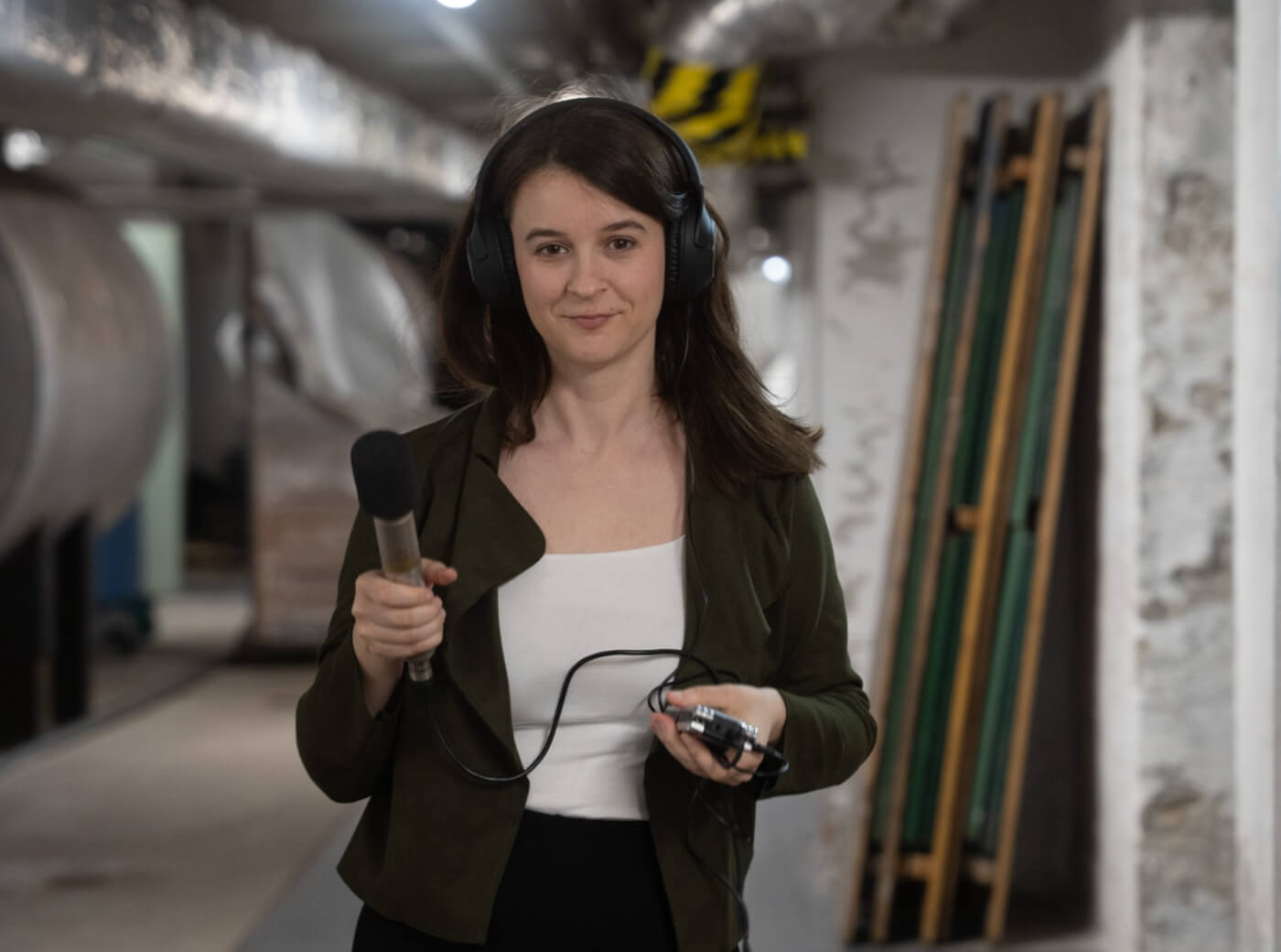 Marlene Groihofer von audioportrait steht in einem Keller oder Maschinenraum mit Audioequipment