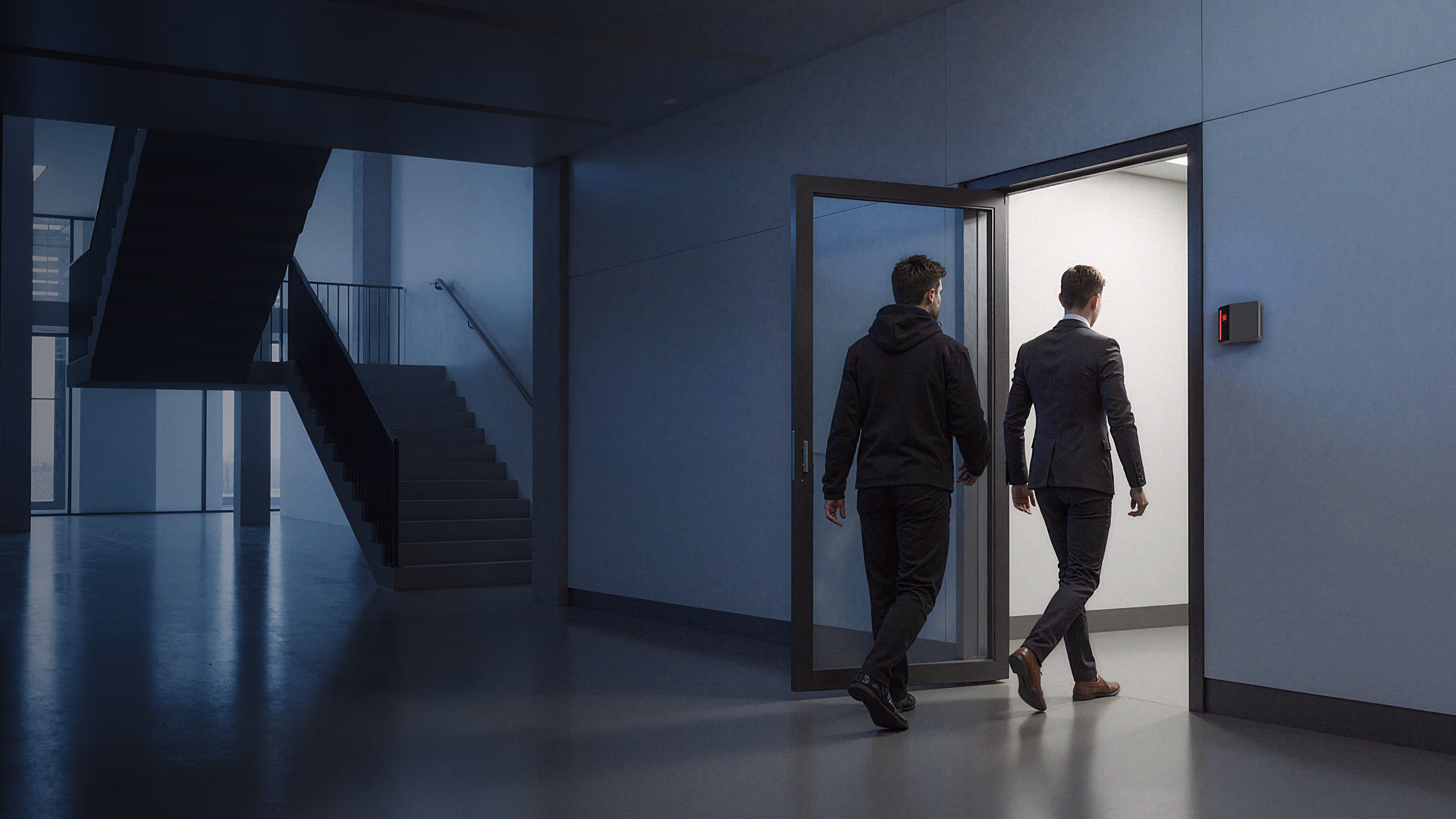 Two men walking through an open glass office door, one following close behind the other, with a black Alcatraz Rock reader mounted on the wall beside the entrance.