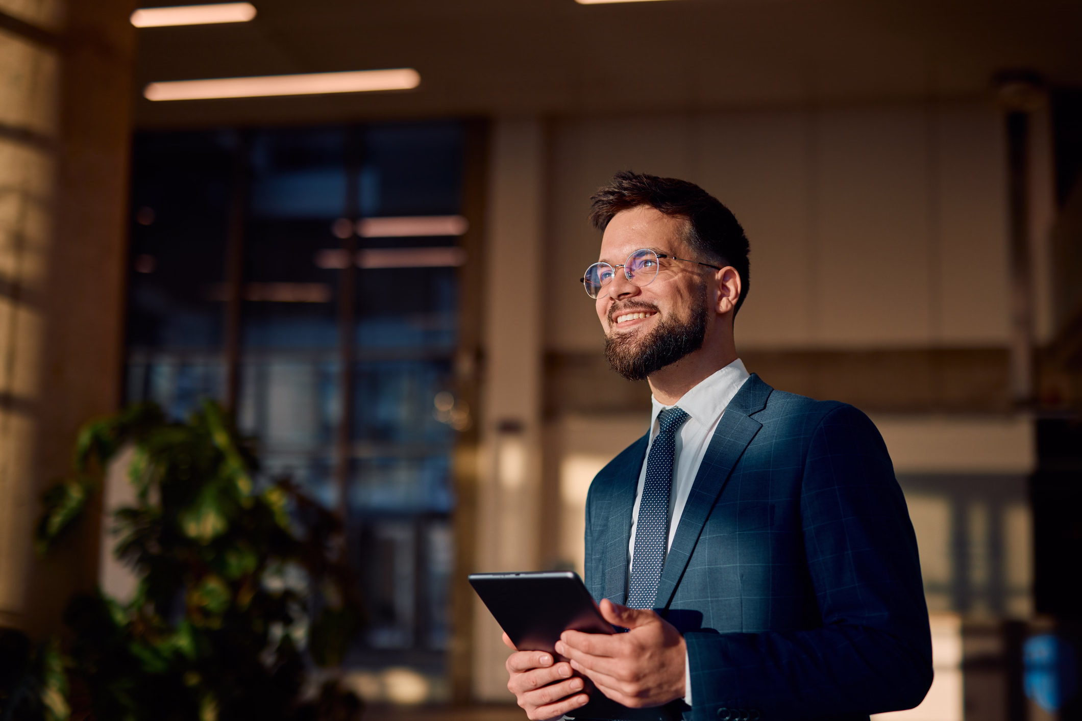 A technology leader holding a tablet in a corporate office