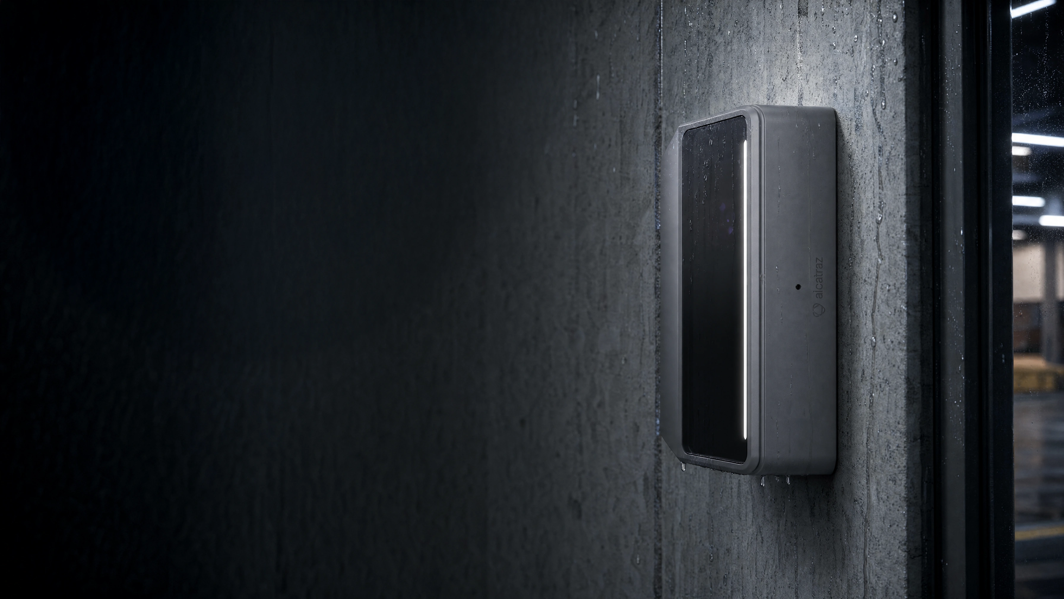 Rock X mounted on a wet concrete wall at an exterior entrance at night, rain falling through the light above it