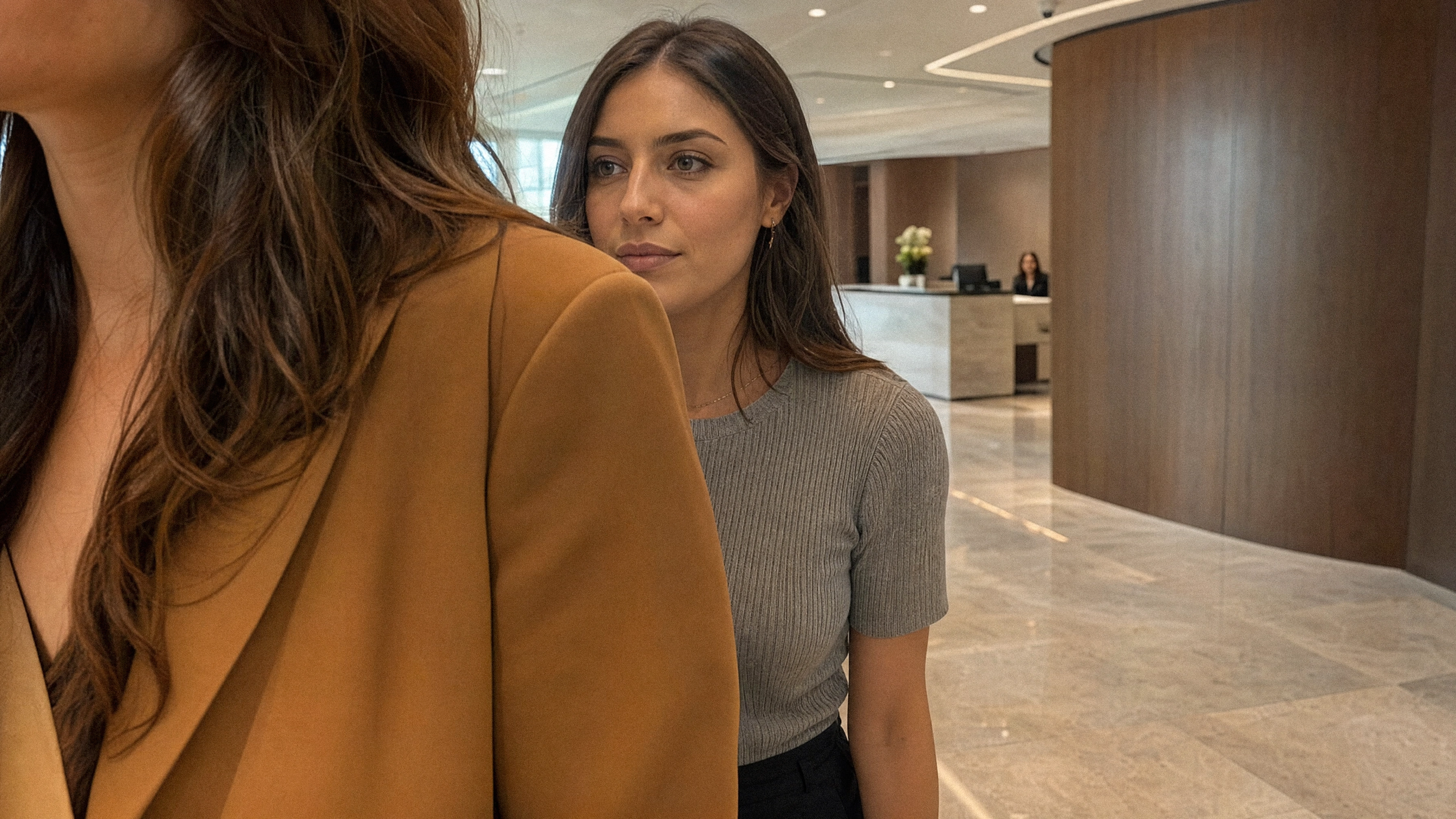 Two women passing each other in a lobby, the follower's face acquired by the reader
