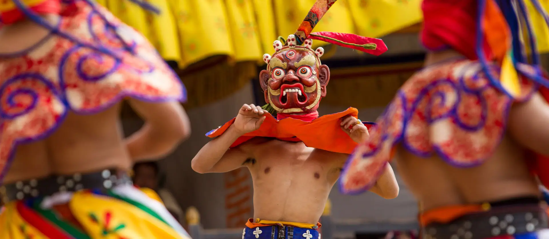Bhutanese masked dancer moving rhythmically during a traditional festival dance performance.