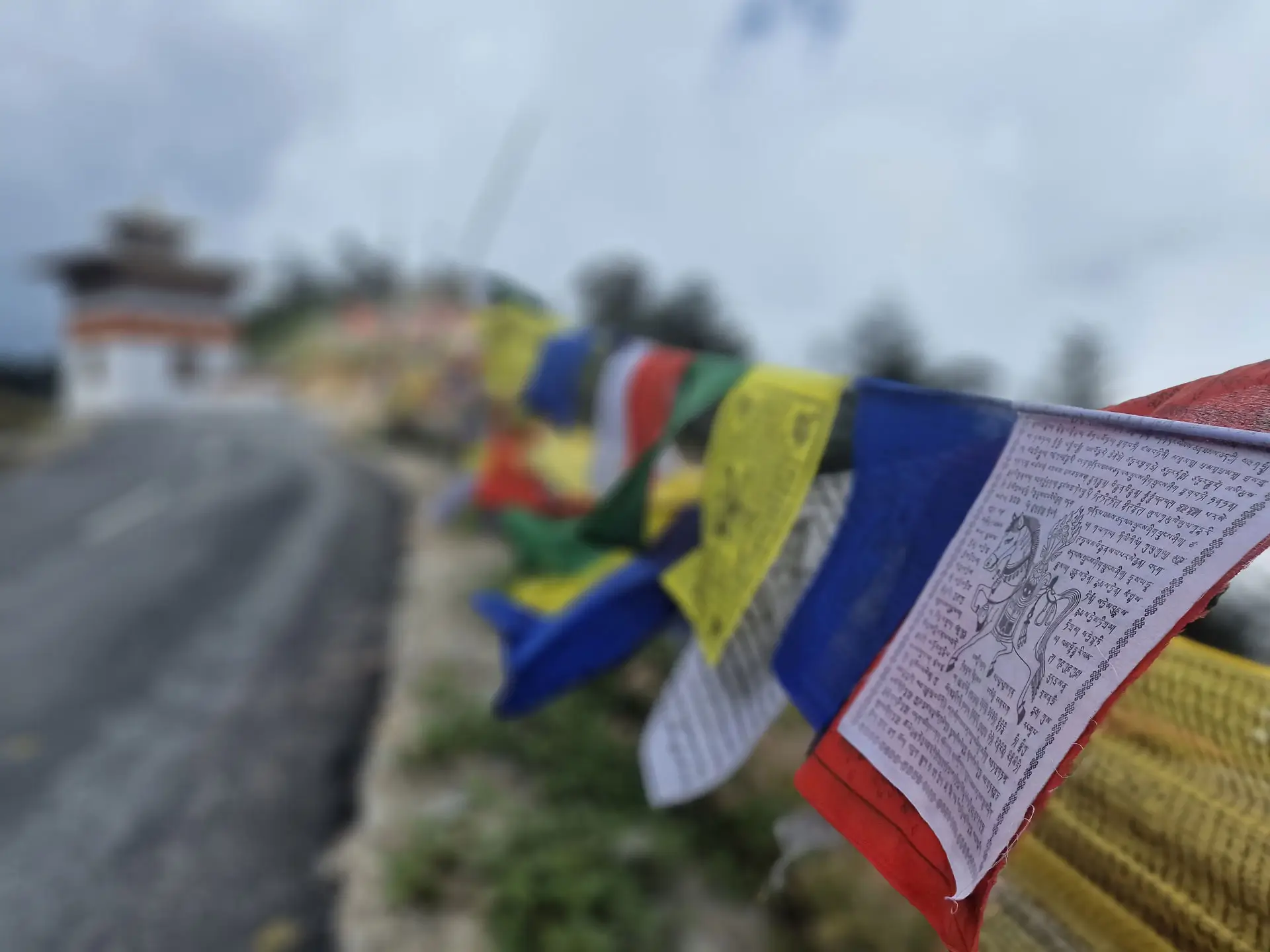 Close-up of colorful Buddhist prayer flags fluttering in the wind along a mountain trail in Bhutan, symbolizing blessings of peace, compassion, and wisdom.