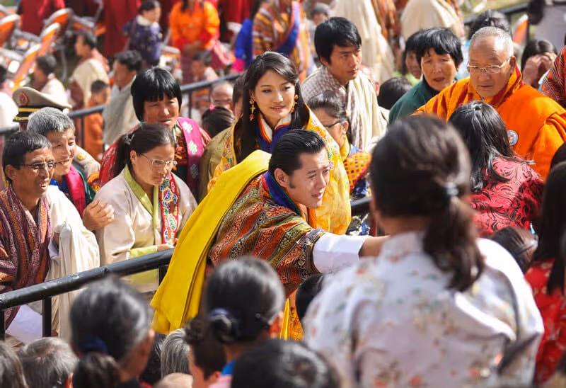 Bhutan’s King and Queen warmly greeting people during a national celebration, symbolizing deep royal connection.