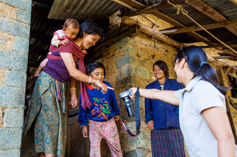 Bhutanese family engaging with a guest, showing genuine connection and rural hospitality.