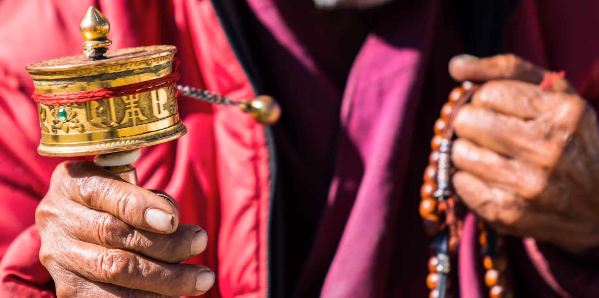 Close-up of prayer wheel and mala beads in a monk’s hands, evoking devotion in Bhutan.