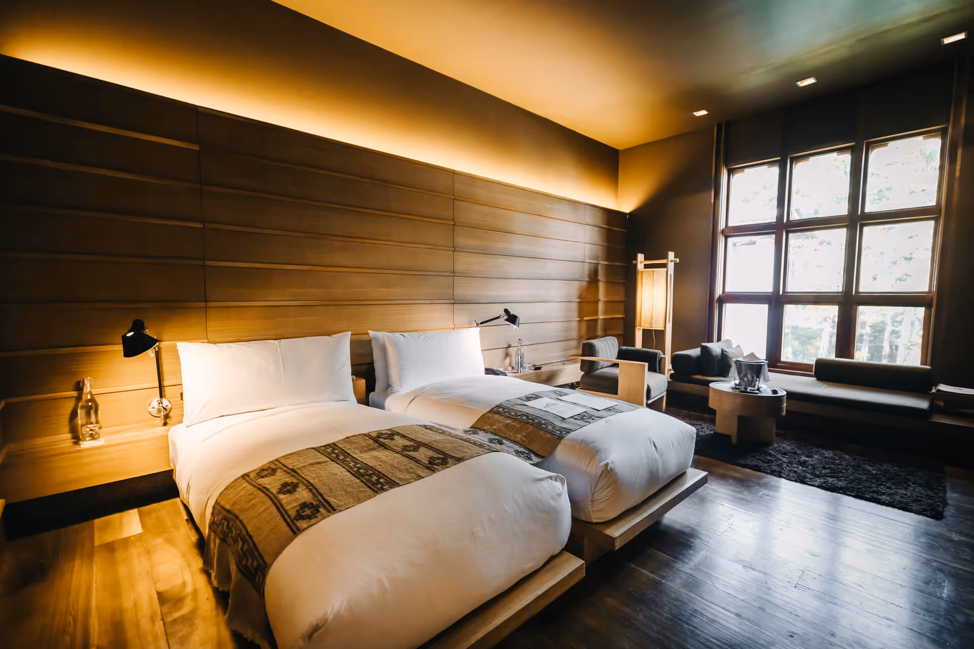 Elegant twin guest room with wood accents and cozy sitting area at a luxury lodge in Bhutan.
