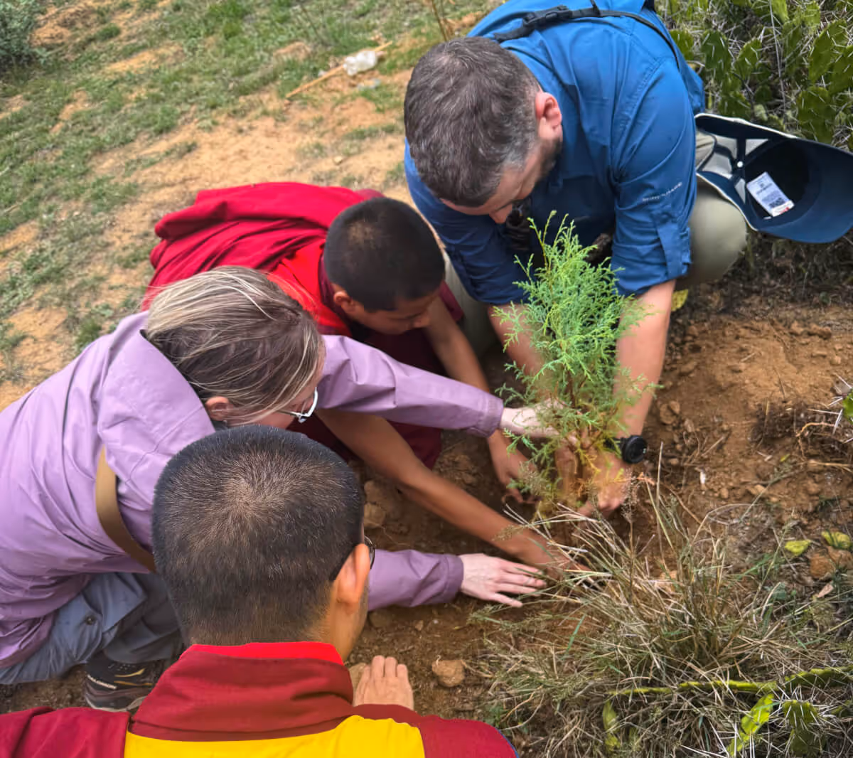 Travelers and monks planting a tree together in Bhutan, supporting sustainable and responsible travel.
